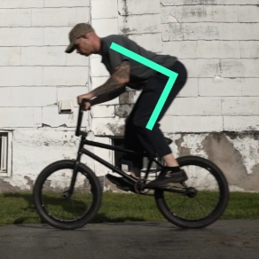 Billy Kennedy hinging at the hips while riding BMX to show the posture with colored bars overlaid on the image to show the angle of the hips.